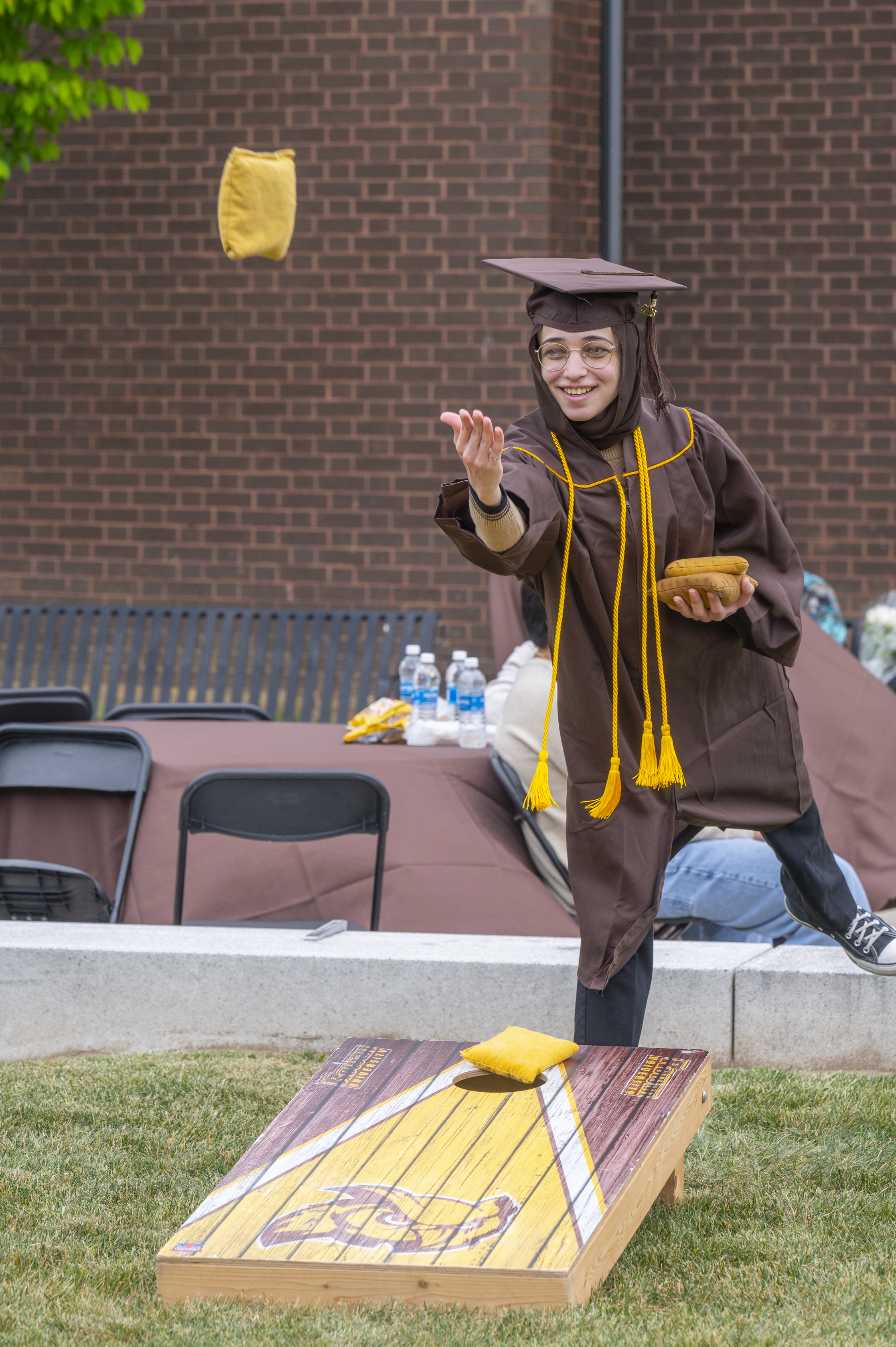 A Rowan University graduate throws a beanbag at a cornhole game. She ...