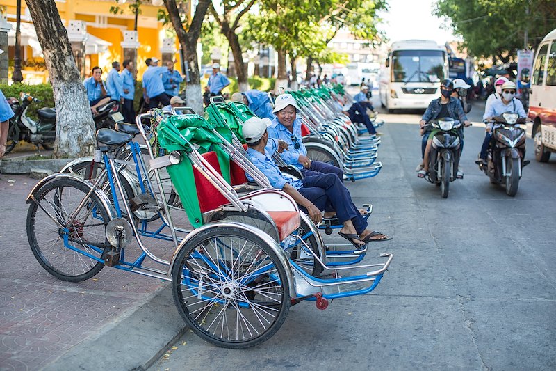 Rikshaw-style bike taxis wait for hoards of tourists to step off their buses.