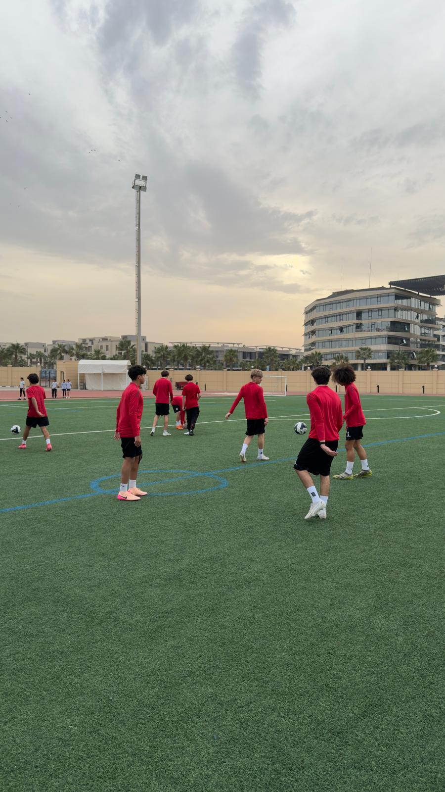 A group of young soccer players practice on a green field. They wear ...