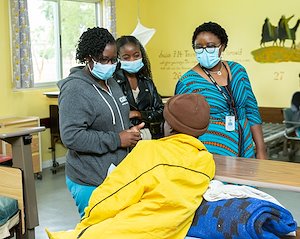 Nurse Matron Juliane, Pharmacy Technologist Christine, and Executive Director Frida, are asking Shadreck how he feels since he has been healed from cleft lip.