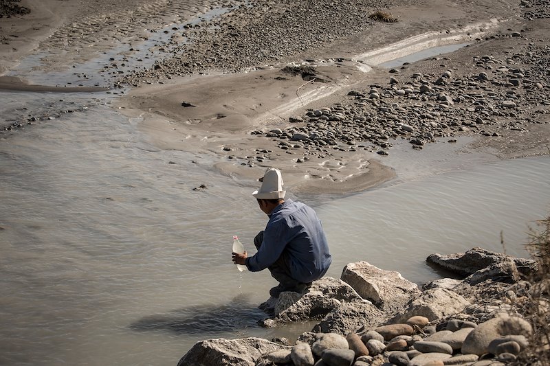 Shepherd Jusubali Jamylbaev fills a bottle with water from River Soh in Aktorpak.