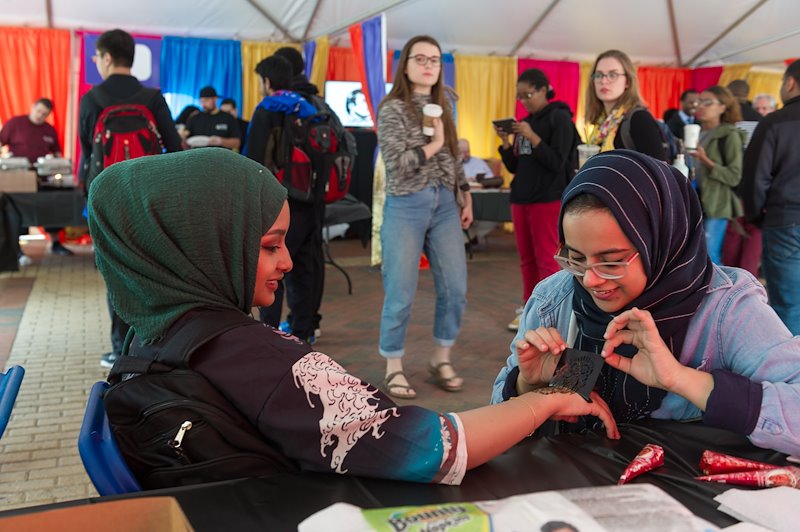 Salma Awad (right) practices the art of henna painting at VCU Qatar Day. Photo by Kevin Morley, VCU University Relations.