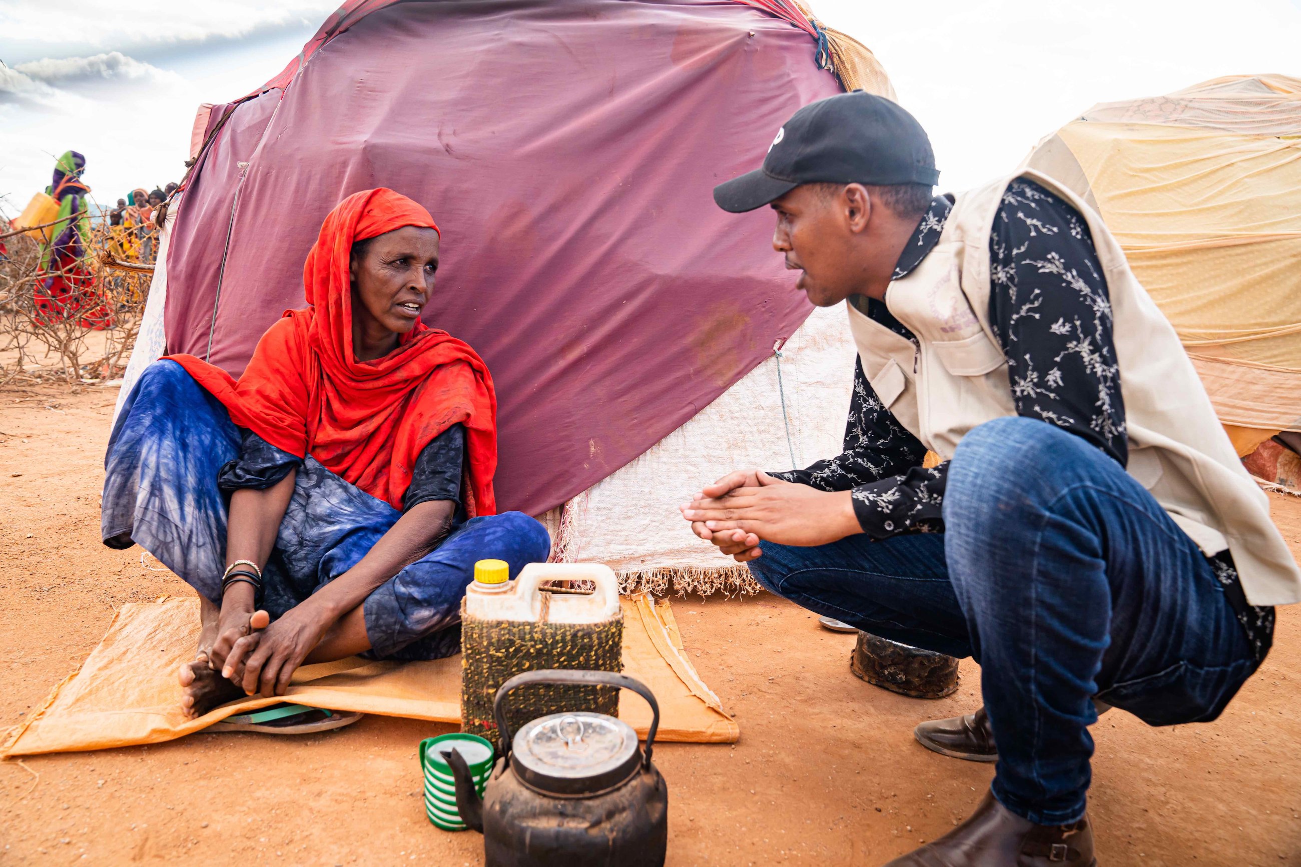 Abdirahman talks to a displaced woman in front of her makeshift home in the Ladan settlement in Doolow.