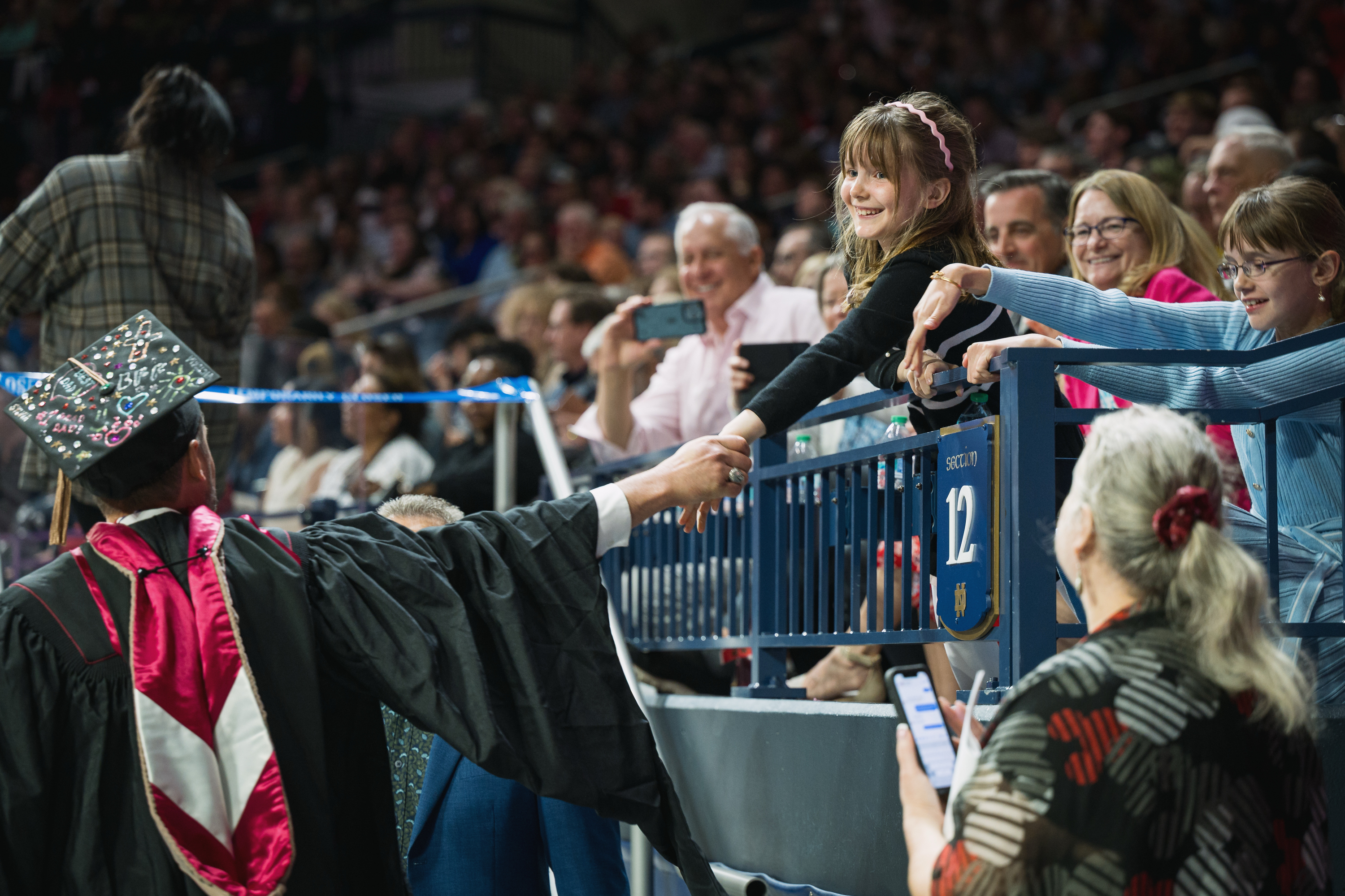 A graduate reaches out to a young audience member during the IU South ...