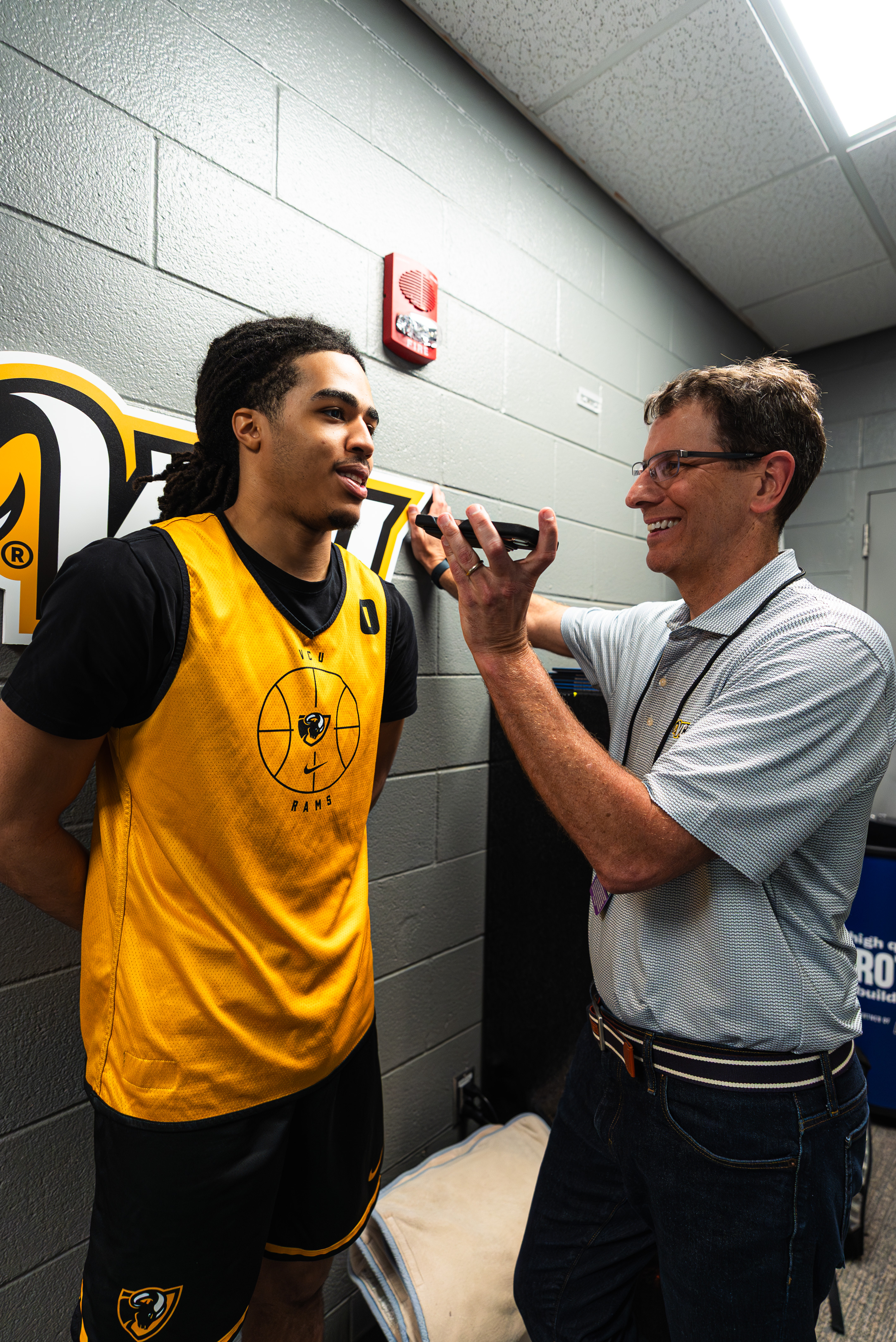 Basketball player in TCU Rams jersey speaks with a smiling man holding ...