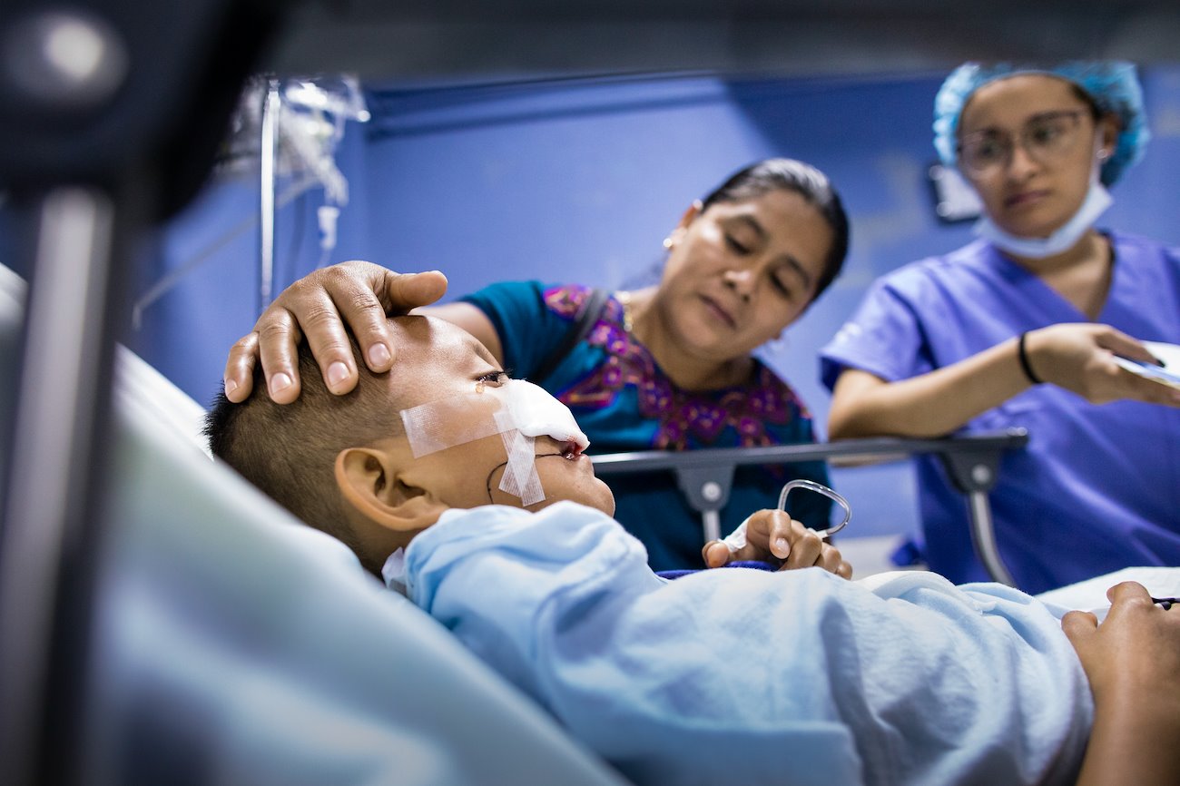 Antony, comforted by his mother, sheds a tear as he recovers from surgery.