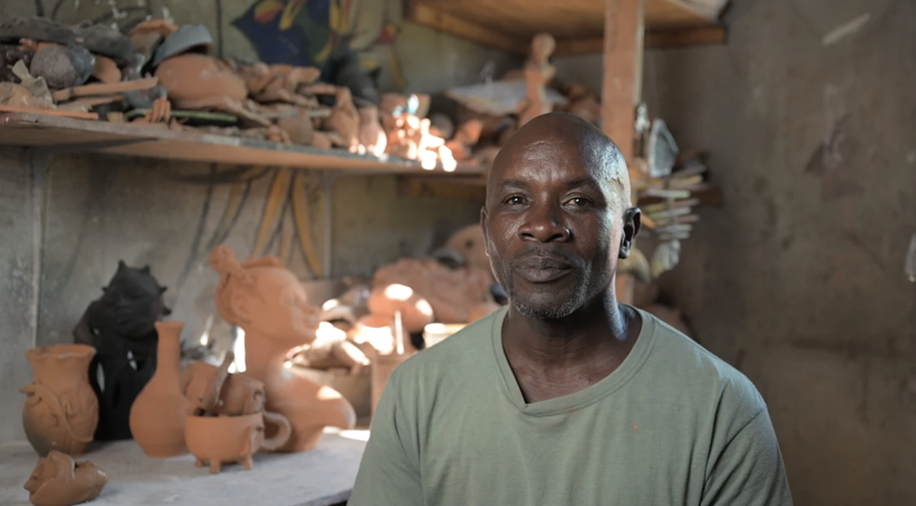 Portrait of a Black man in a green t-shirt, standing in his workshop ...