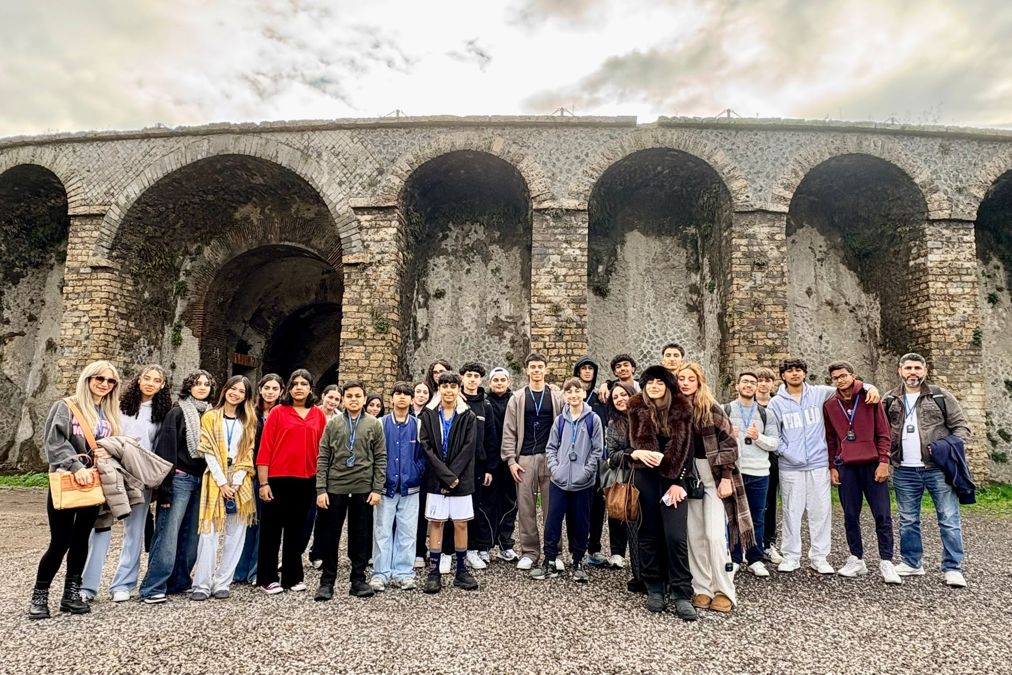 Group of students and adults pose in front of ancient Roman aqueduct ...