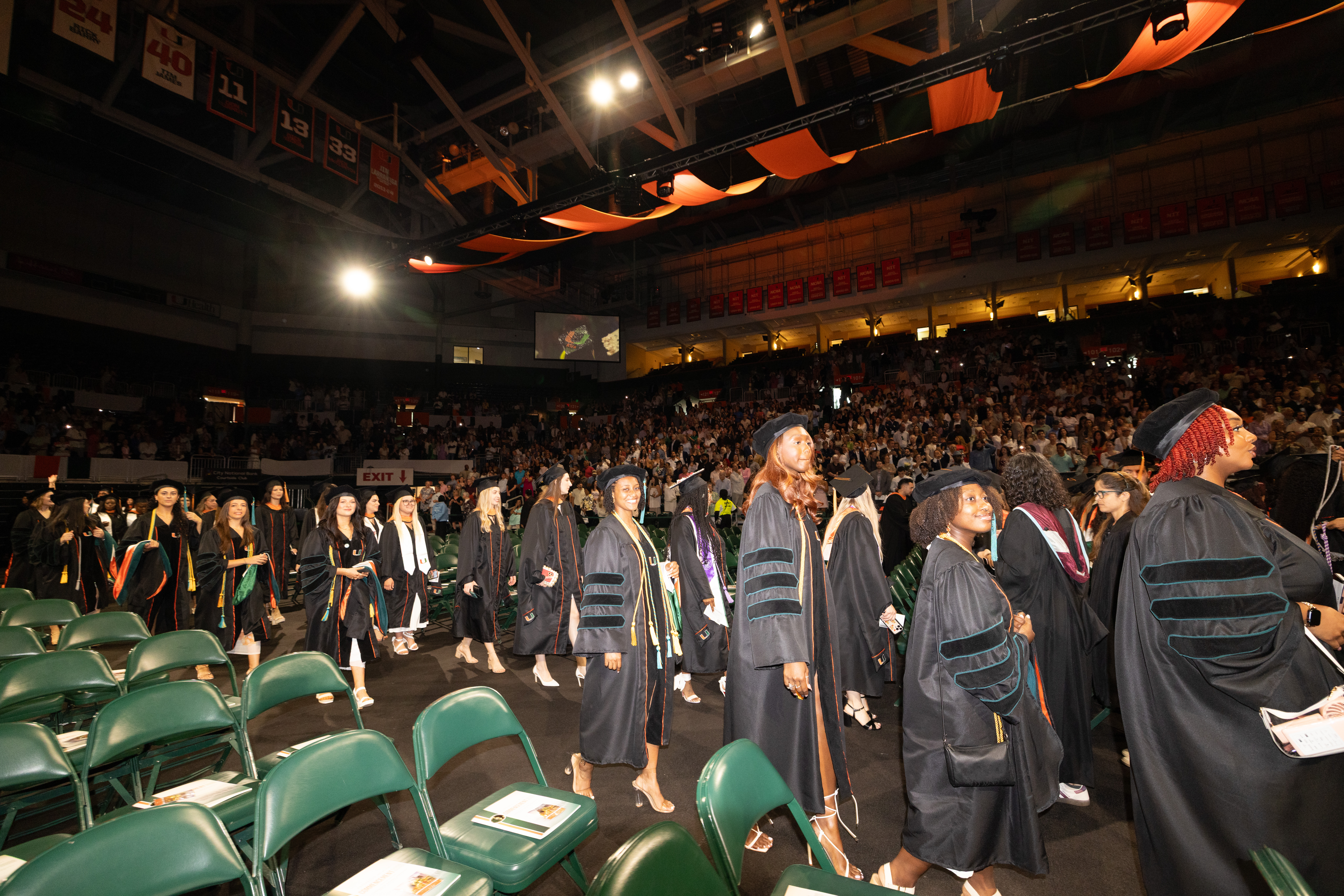 Graduates in black gowns walk in a line at the Spring 2026 Commencement ...