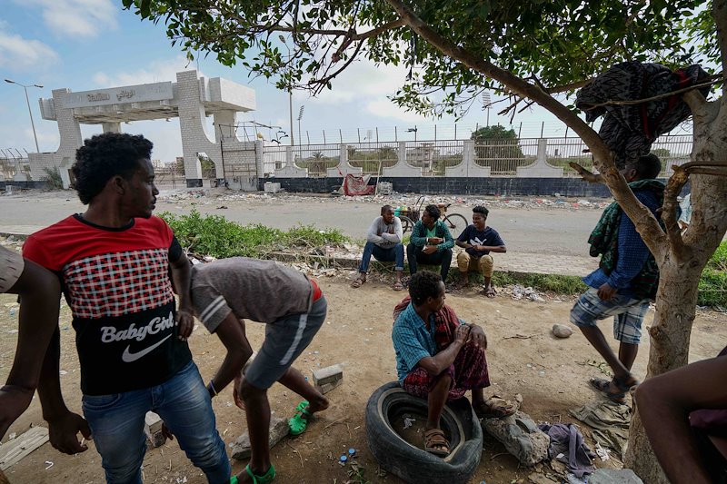 East African men gather at a former football stadium in Aden. The stadium now serves as a well-known meeting place for migrants and refugees who are making their way through Yemen towards Saudi Arabia and beyond.