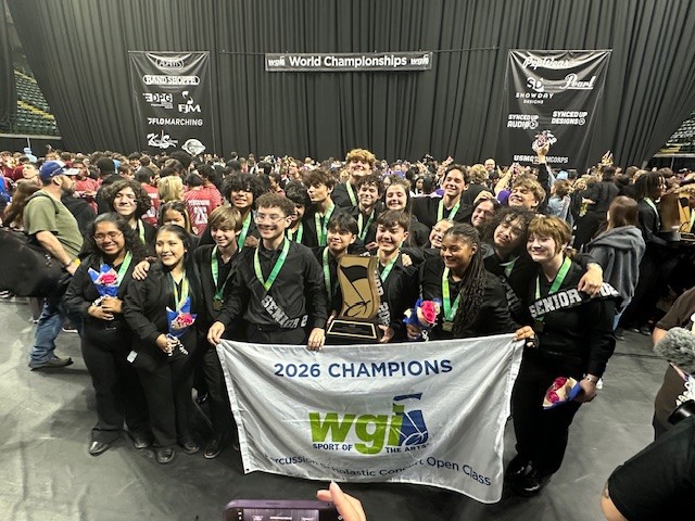 A large group of young people pose with a trophy and banner that reads