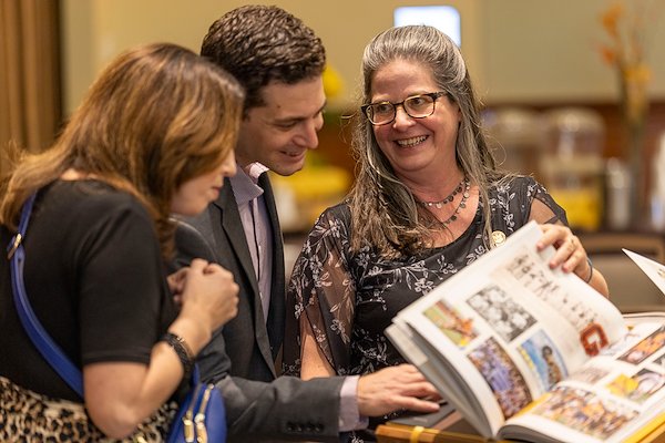 At the book launch festivities, alumni, colleagues and Rowan family members gathered around  the book displays. Below, Erin Pimpinella, Steve Pimpinella ’05 and Debbi Denton ’92.
