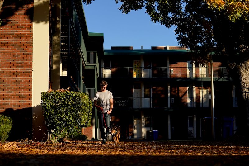 Lincoln Hooper walks his dog Marden outside Sycamore Hall. Hooper currently resides in the dorms after his family lost their hone due to the Creek Fire.