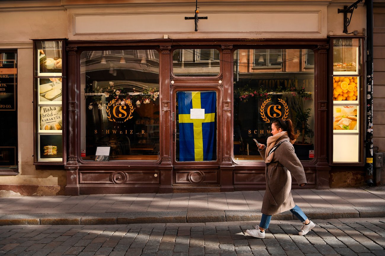 A pedestrian passes the closed Schweizer Cafe, which has a sign in the window saying the will be closed until herd immunity is reached, in Stockholm, Sweden, on Thursday, March 26, 2020.