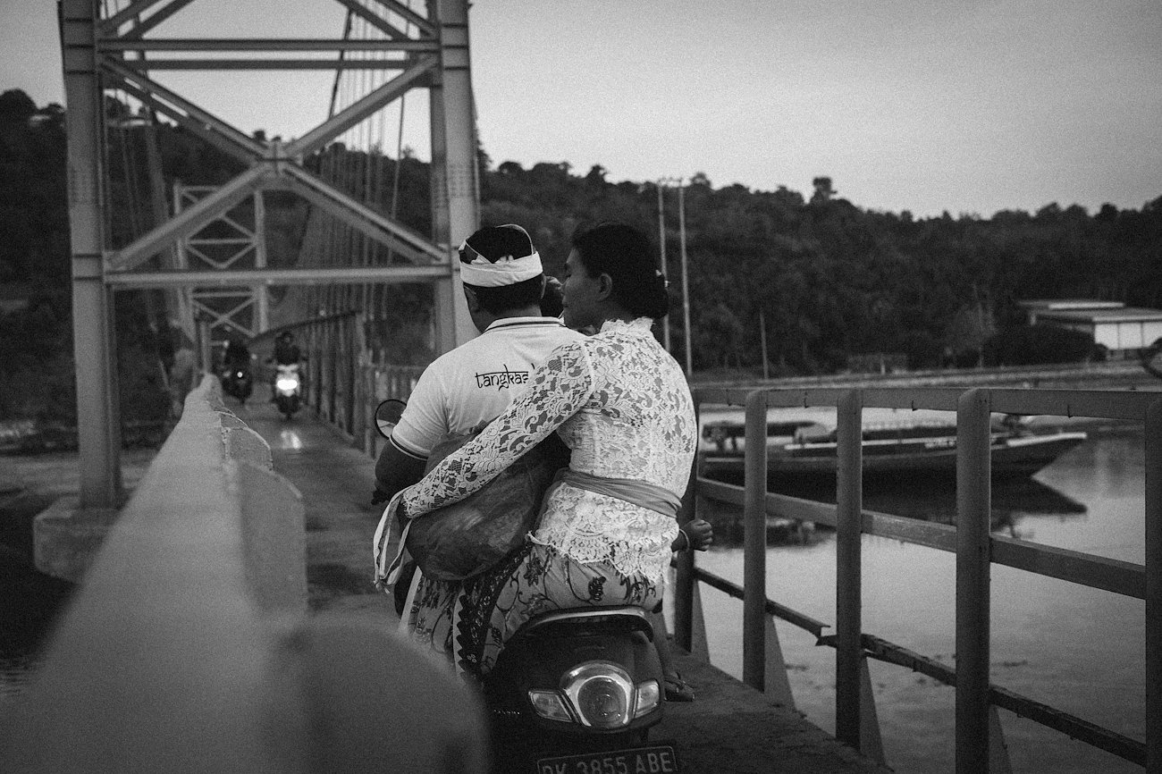3 people are riding a motorbike across the Yellow Bridge, Nusa Penida
