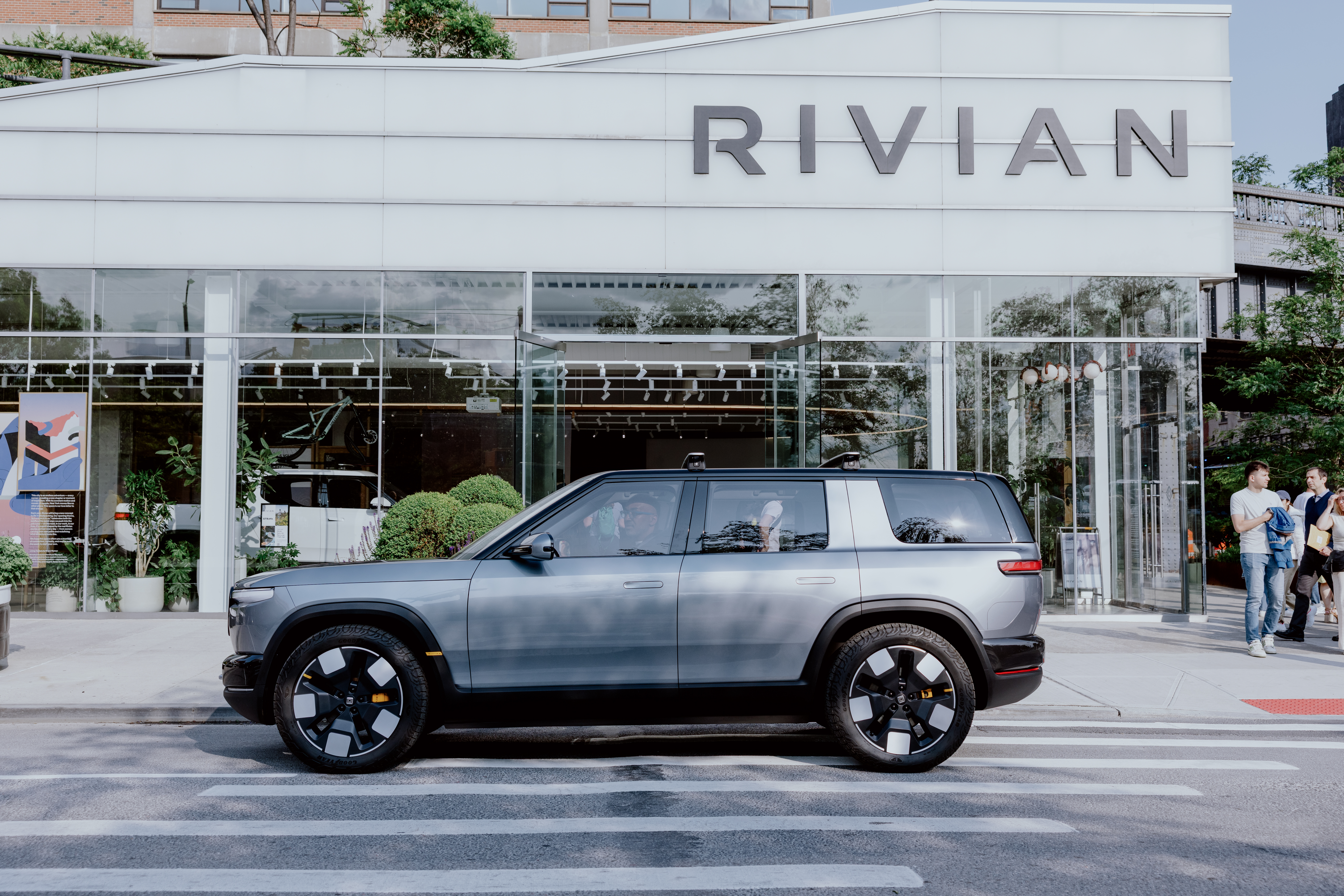 Rivian SUV parked on a city street in front of a Rivian store. The ...
