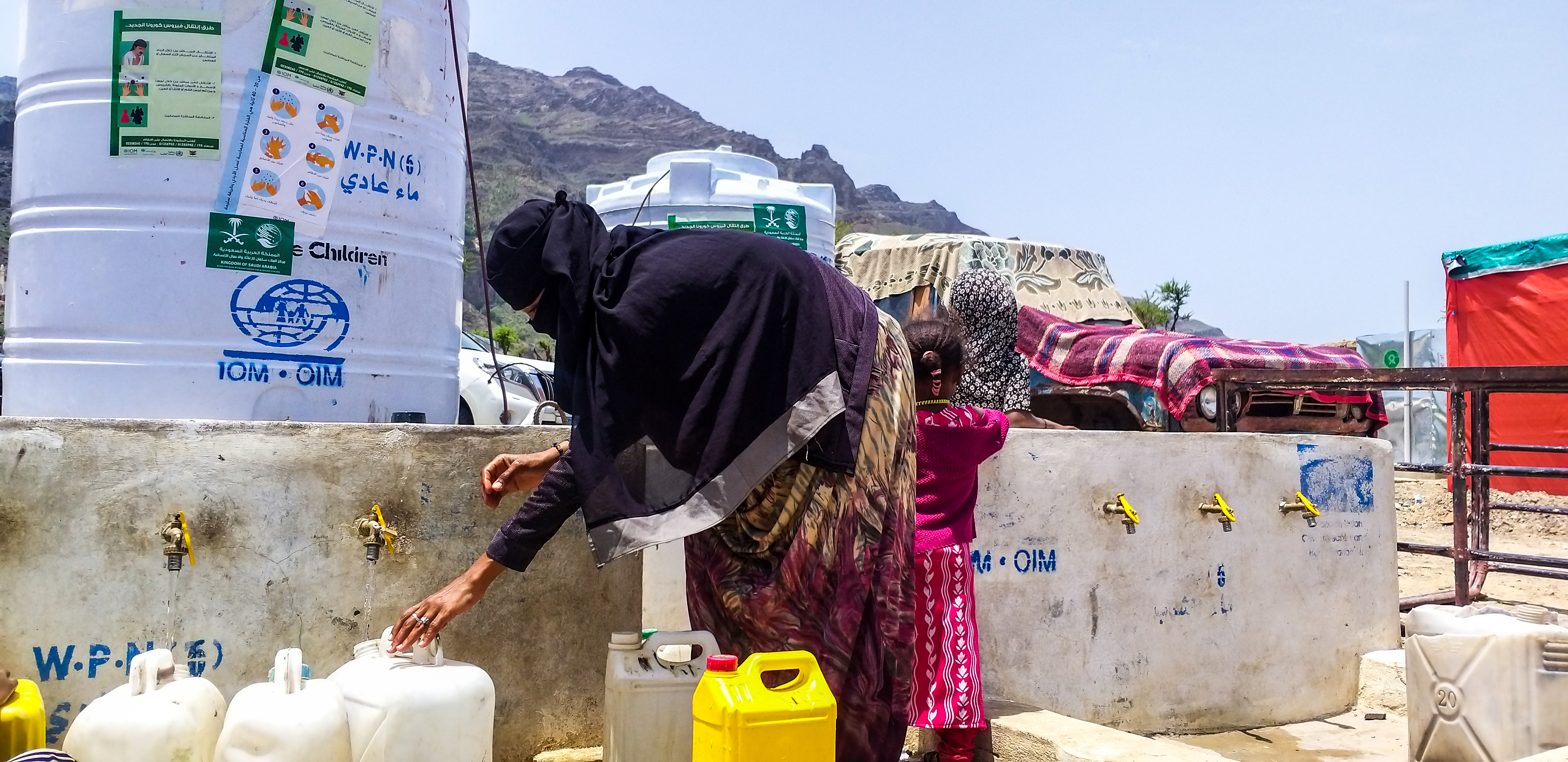 Alhan filling jerry cans at the water tank supported by IOM and KSA next to her shelter. Photo: A. Zabl/IOM 2020