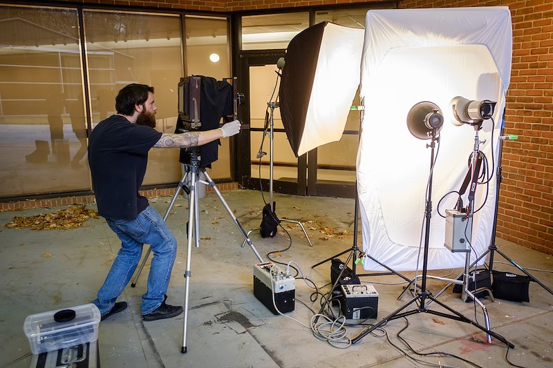 Visiting photographer CJ Harker positions the Eastman camera and portable lights outside of Scales for a hands-on tintype photography class.
