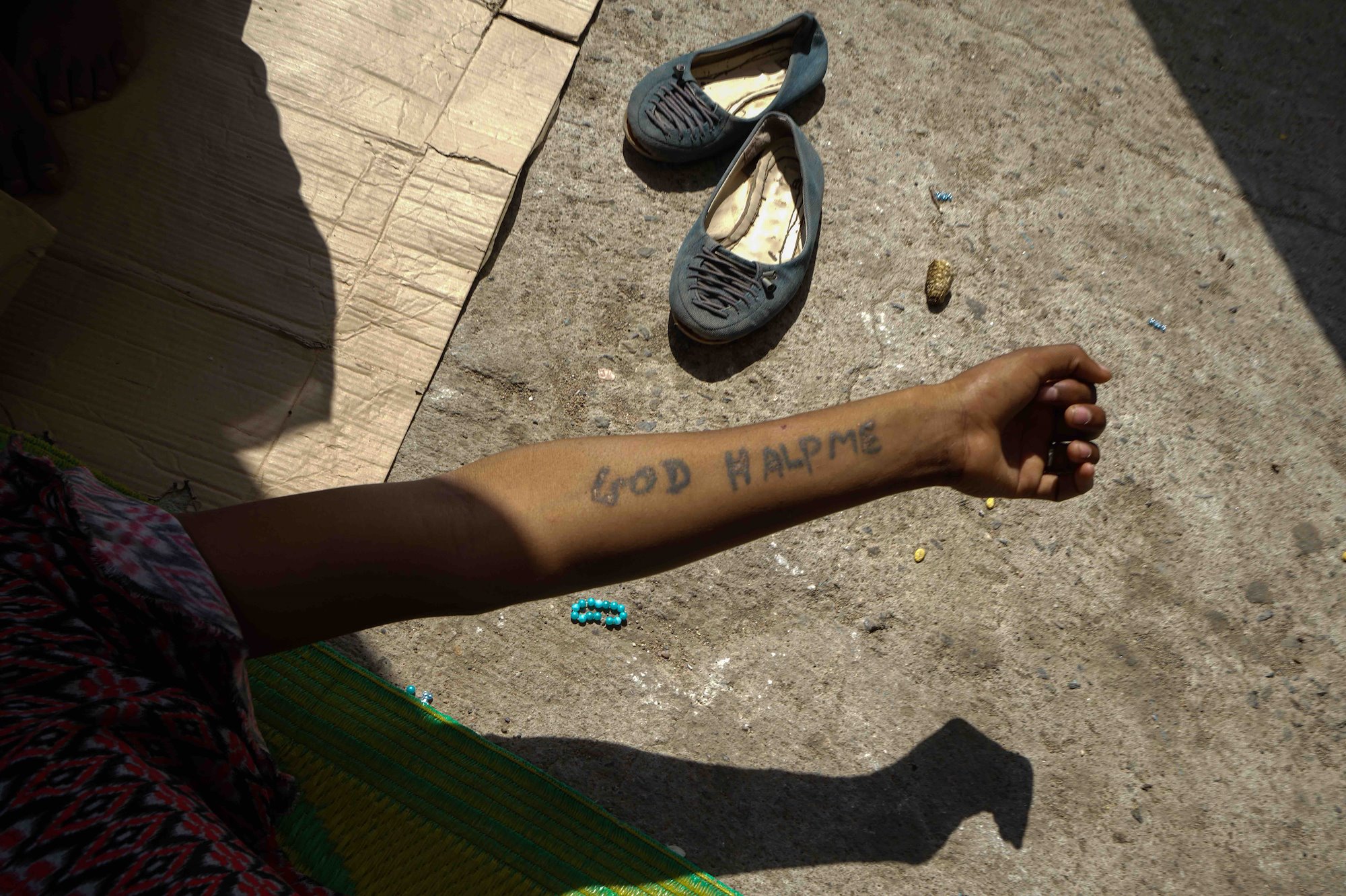 The words 'God Halp Me' tattooed on the arm of a young East African man at a shelter in Aden, on Yemen's south coast.