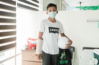 Jhon is happy to receive a CURE bag filled with goodies and a football from our friends and donors.