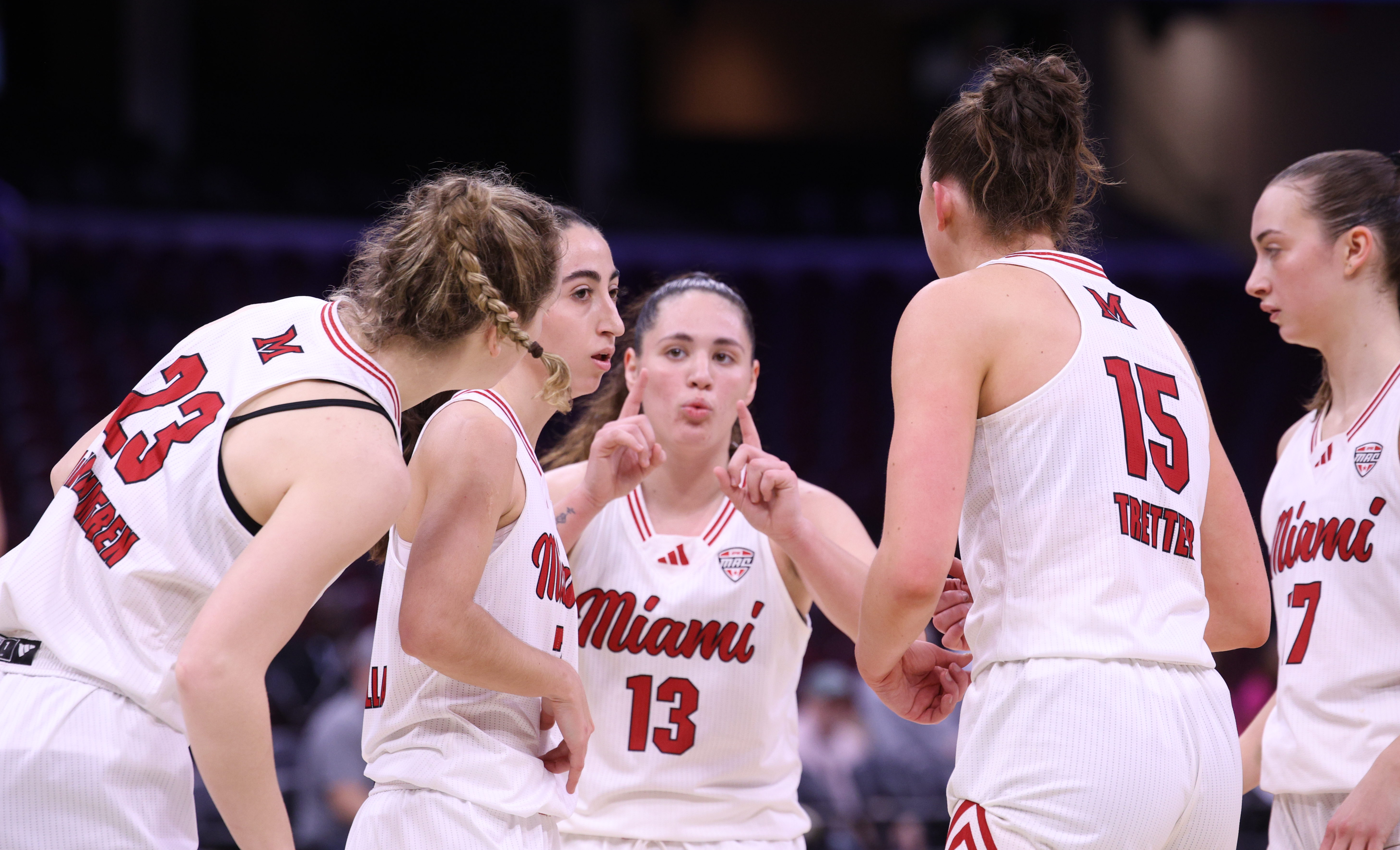 A huddle of Miami University women's basketball players in white ...
