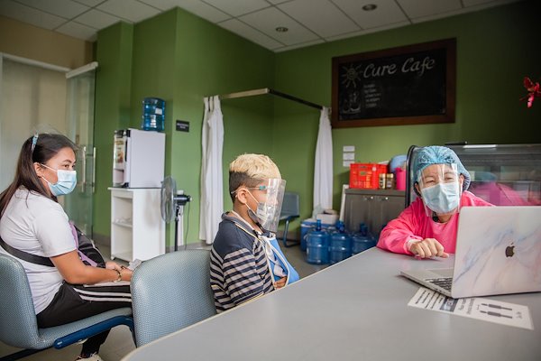 Director of Nursing Ester reads a get-well message from our supporters to CUREkid Jhon.