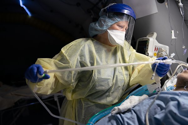 Claudia, a night shift ICU nurse, adjusts a patient's tubes.