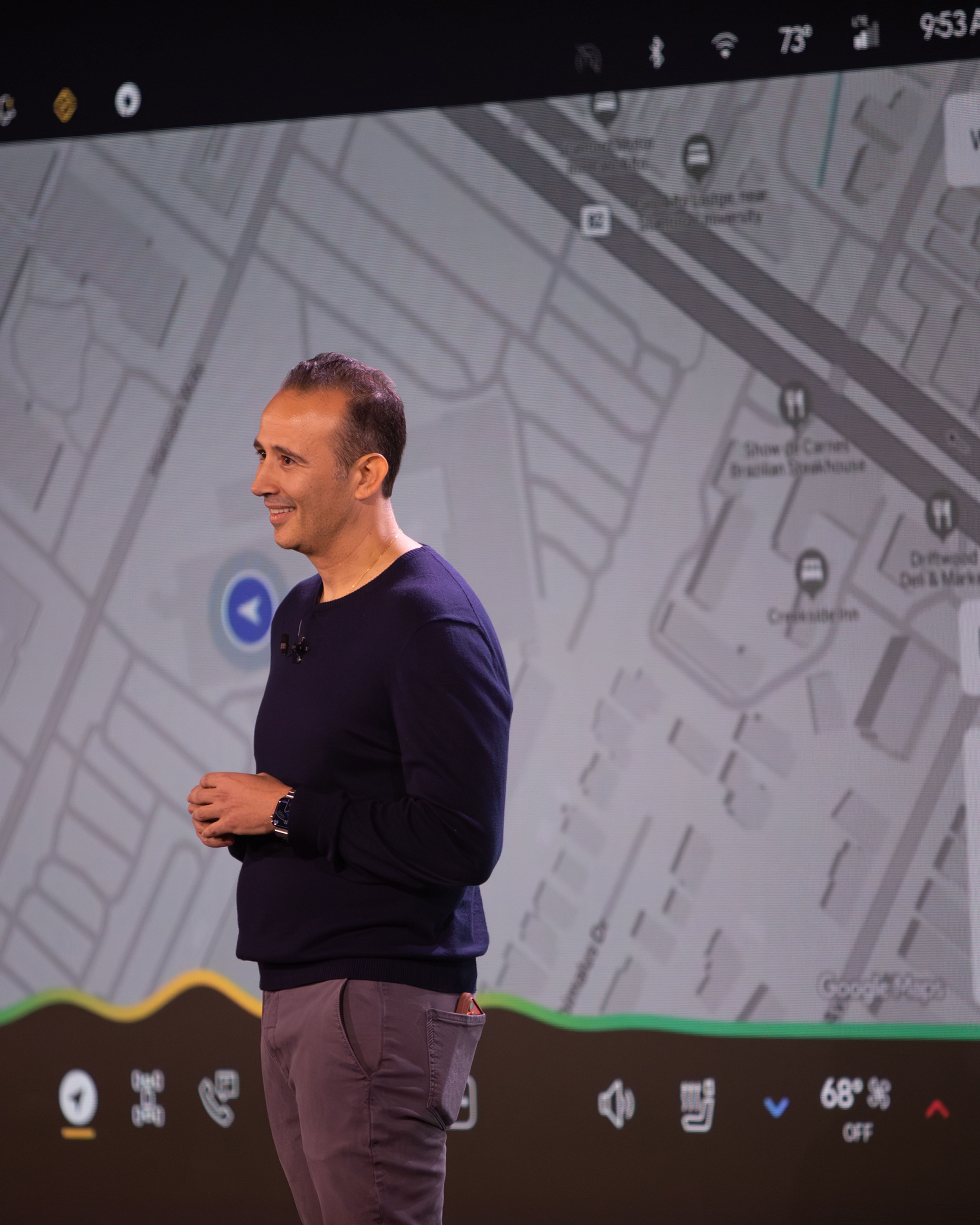 Man smiles on stage in front of large display showing map, likely at ...
