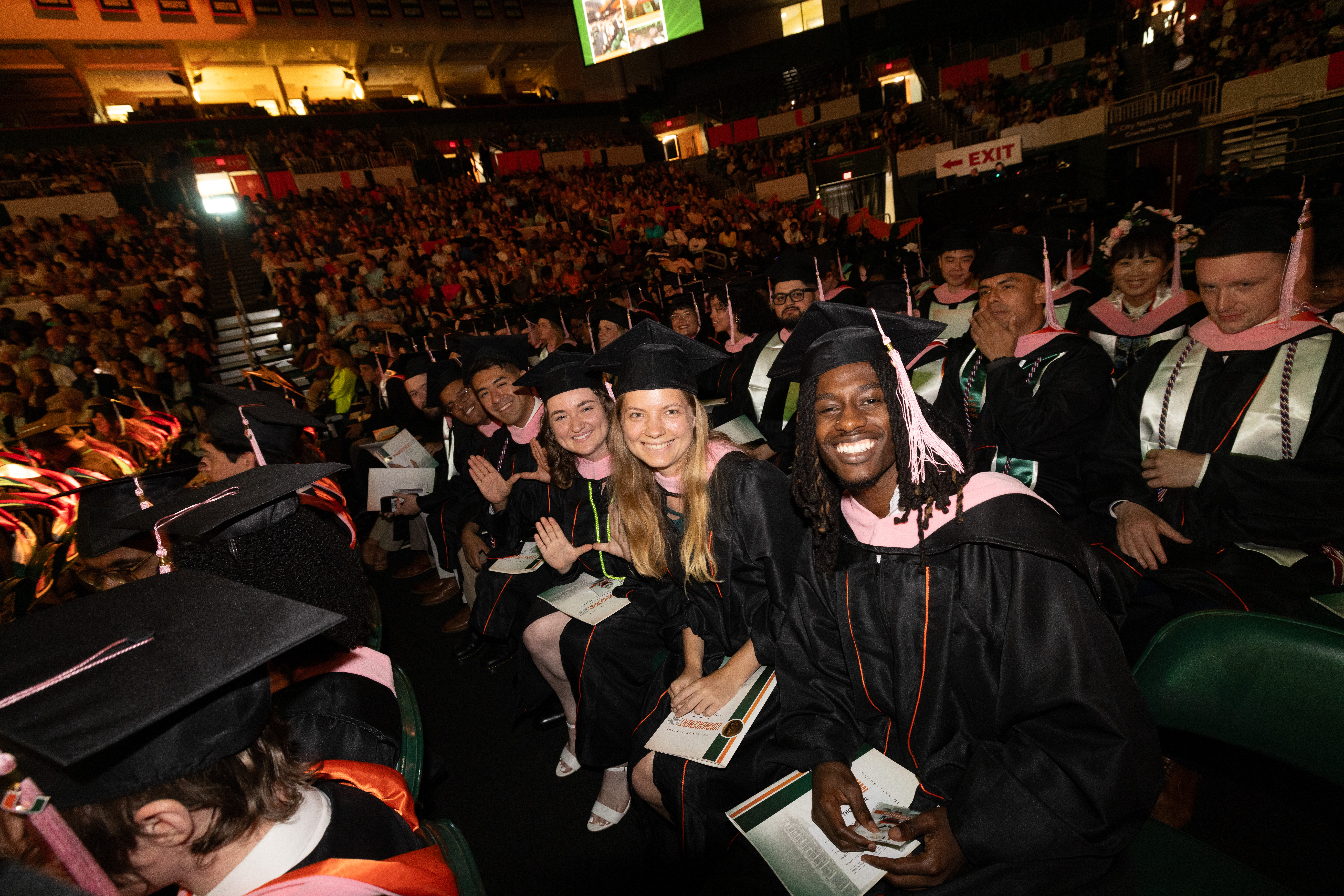 Graduates in black gowns and caps sit in rows at the Spring 2026 ...