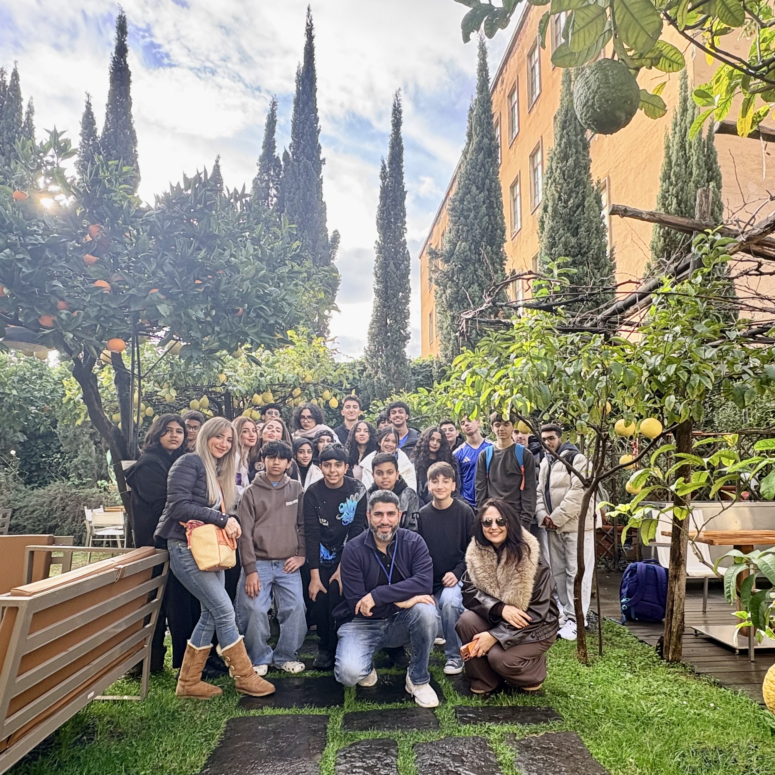 Group of students and teachers pose in an Italian garden. Orange and ...