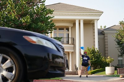 A student acknowledges car passengers outside the Smittcamp Alumni House during the New Student Convocation parade