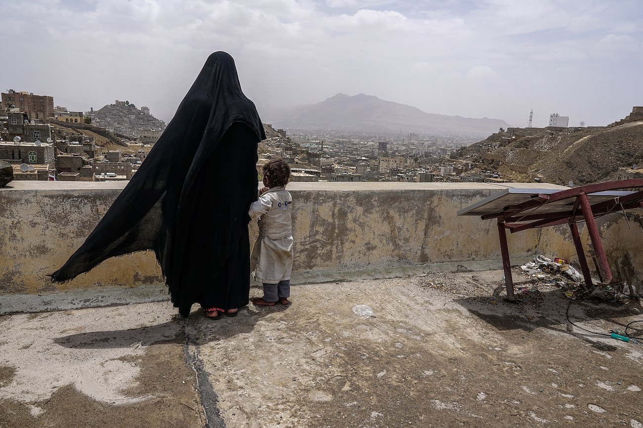 A displaced mother and her daughter look over the city of Sana'a from the roof of their new home. Twenty-three IDP families, all of whom fled fighting in the northern part of the country, now call this dilapidated building their home. ©UNOCHA/Giles Clarke