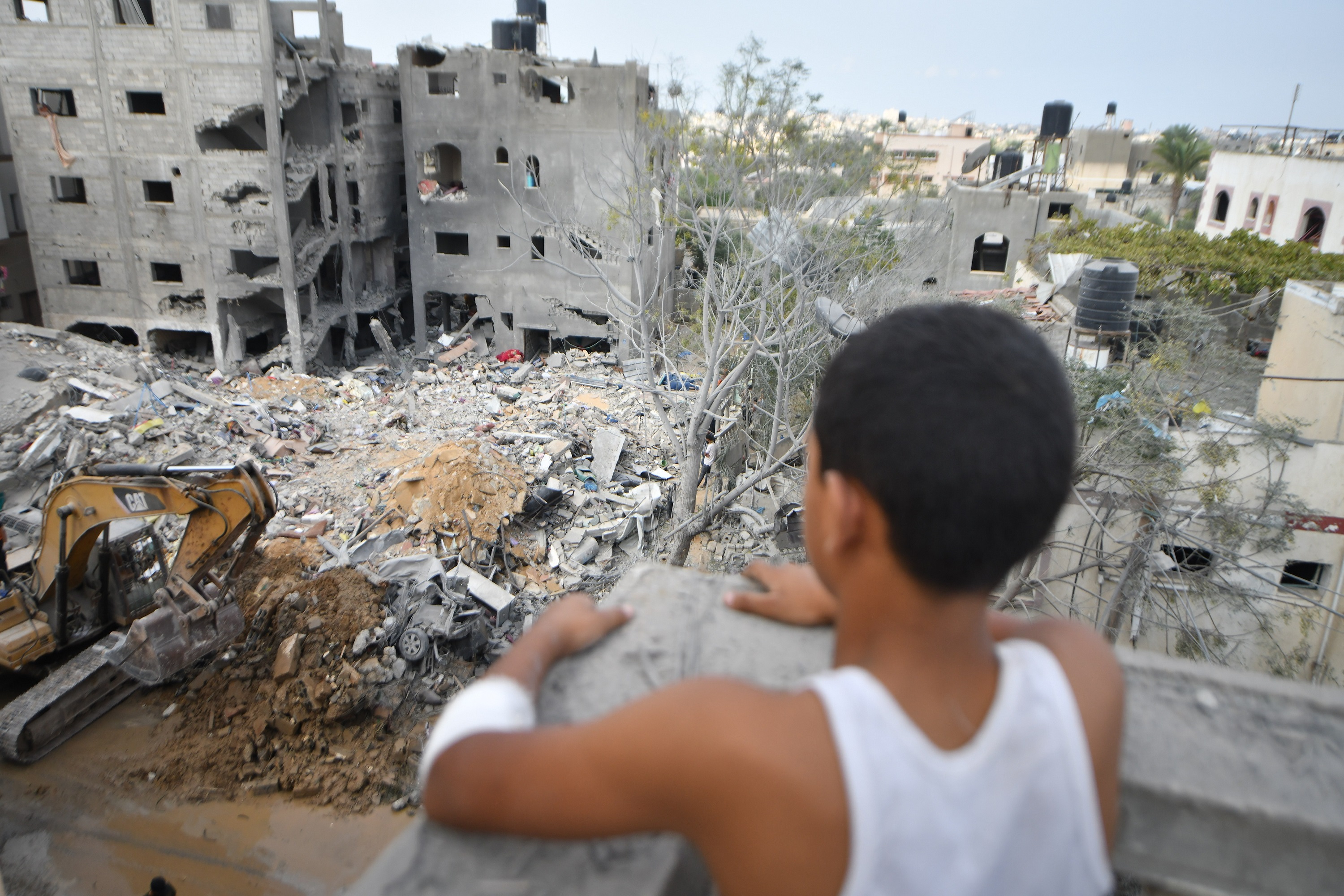 Boy looks over a destroyed neighborhood with rubble, damaged buildings ...