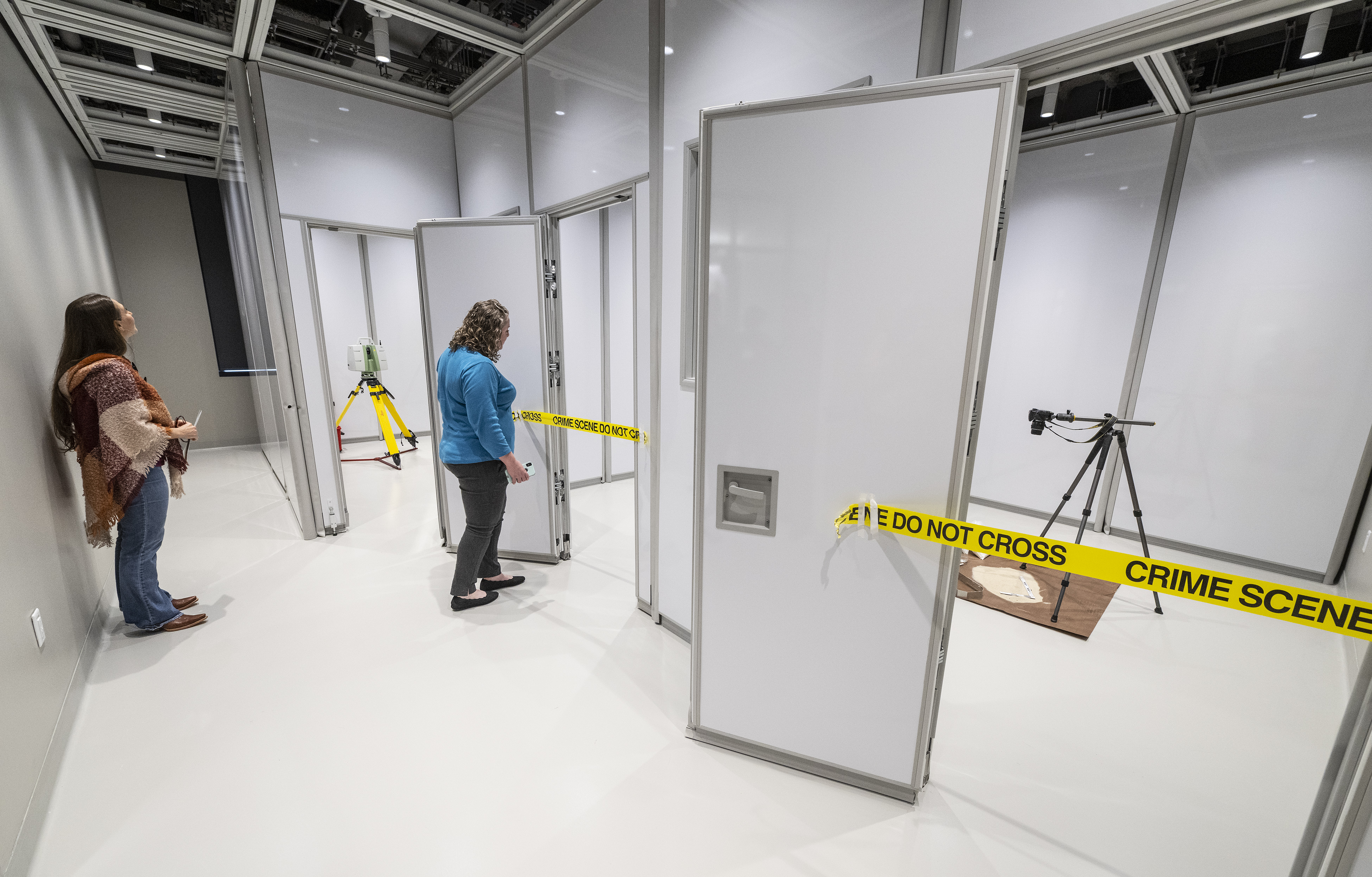Visitors check out the crime scene lab, in which several open doors are ...