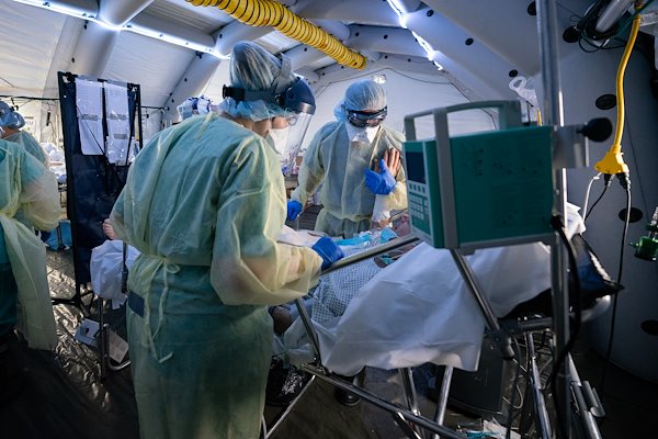Dr. Bob, right, speaks with and comforts an improving patient in the ICU at the SP field hospital for coronavirus patients in Cremona, Italy.