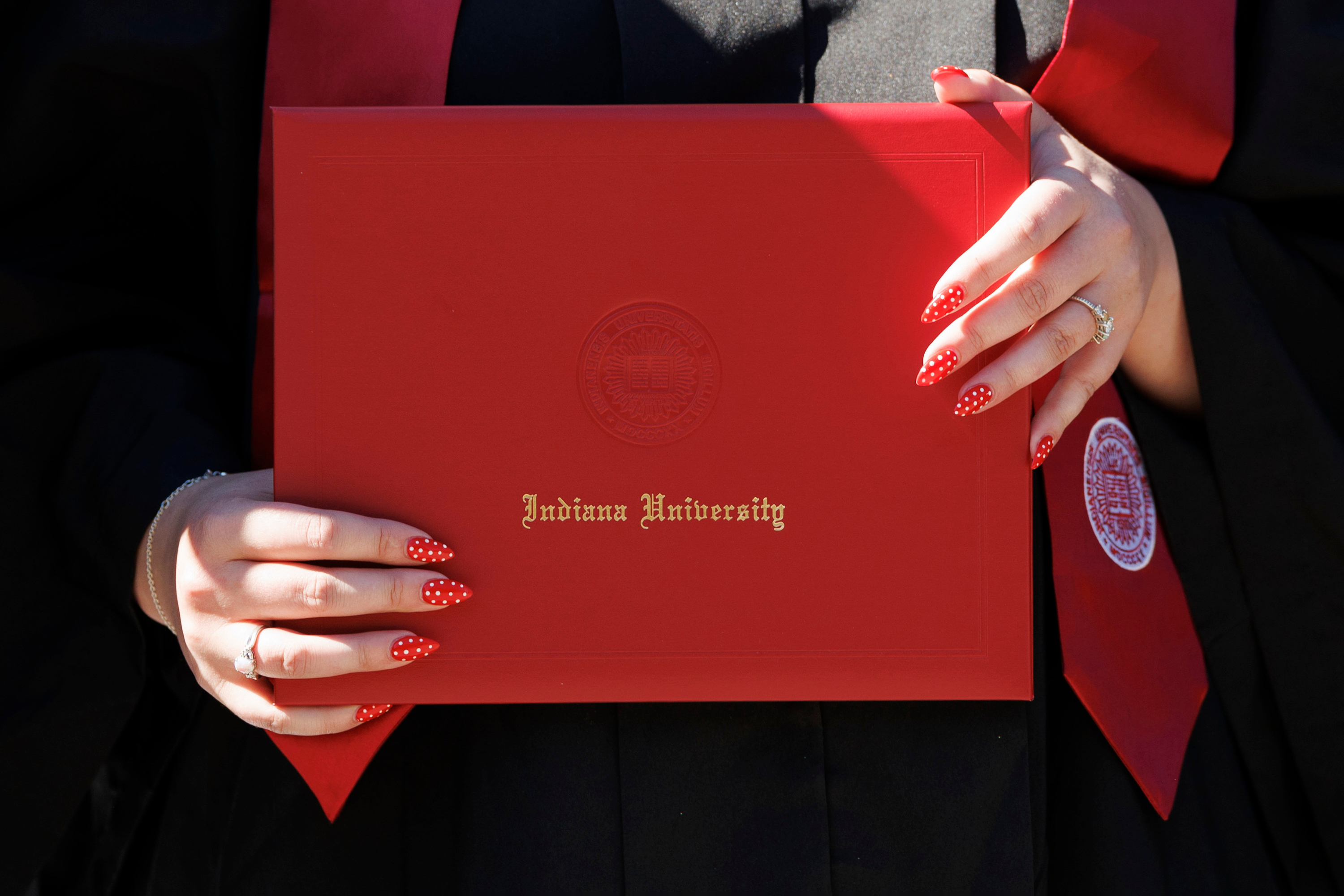 A graduate receives her diploma cover during the IU Southeast ...