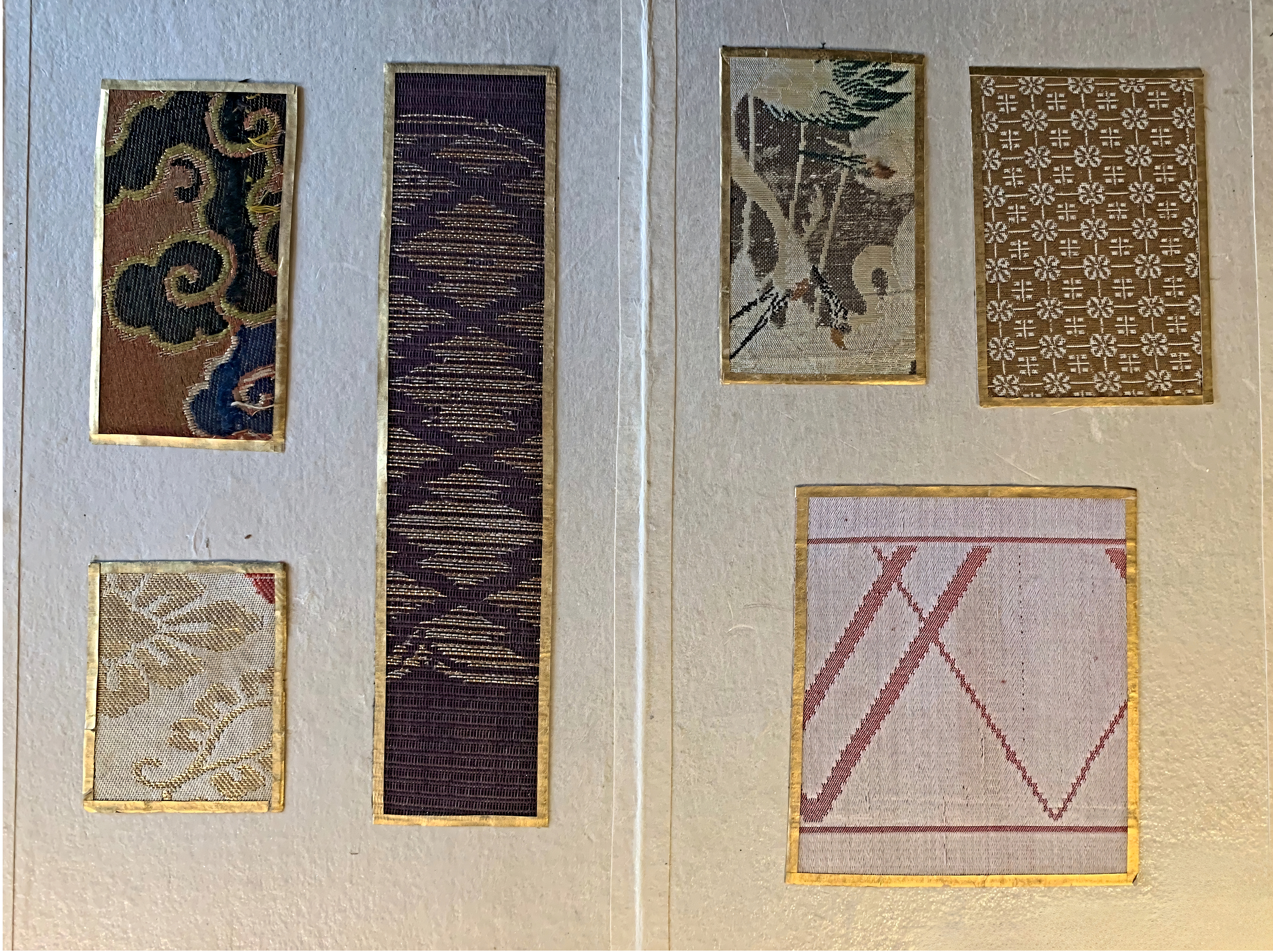 Six Japanese textile swatches with gold borders are arranged on a light ...