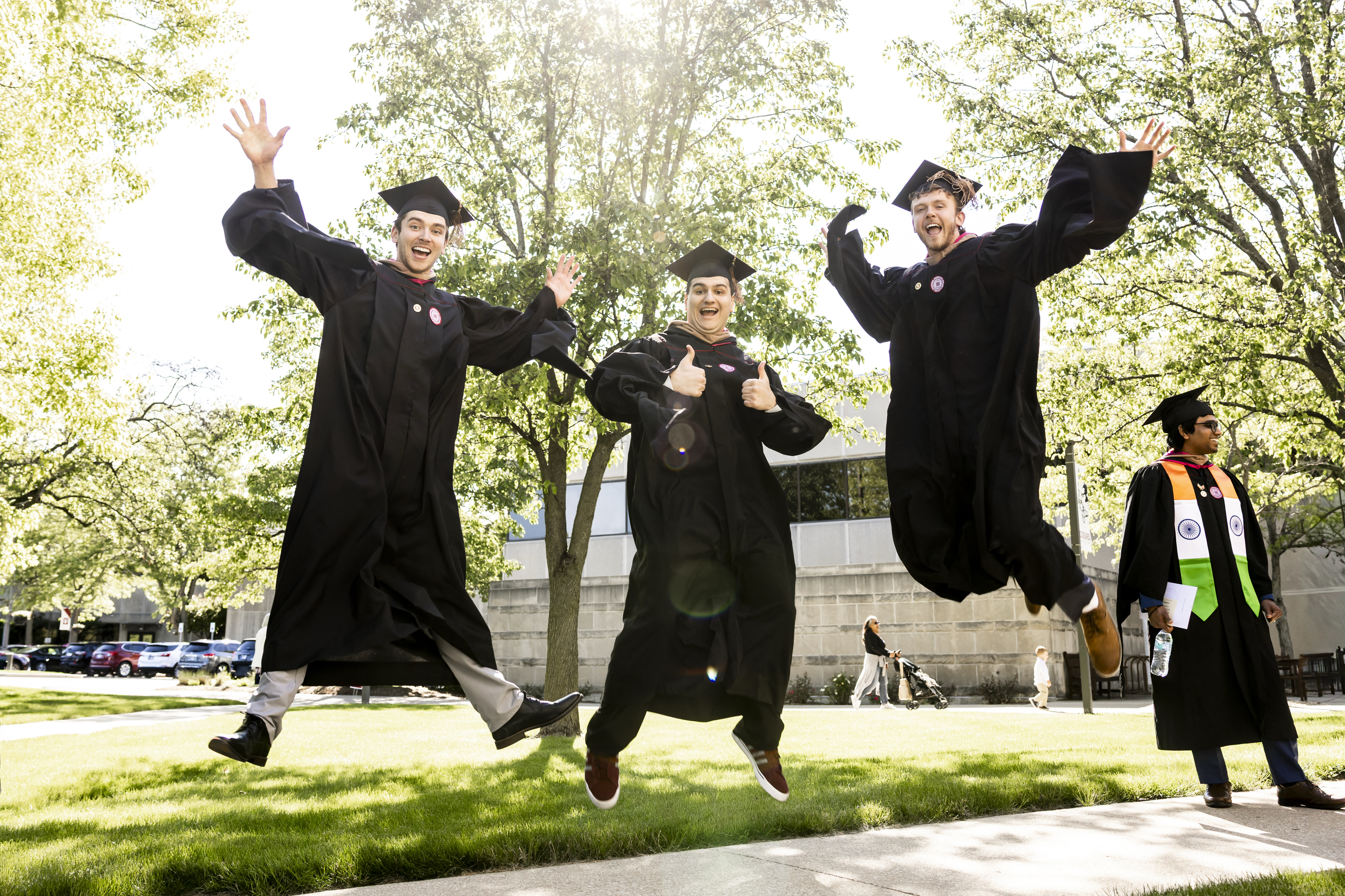 Graduates jump in the air during the processional at the IU Kokomo ...