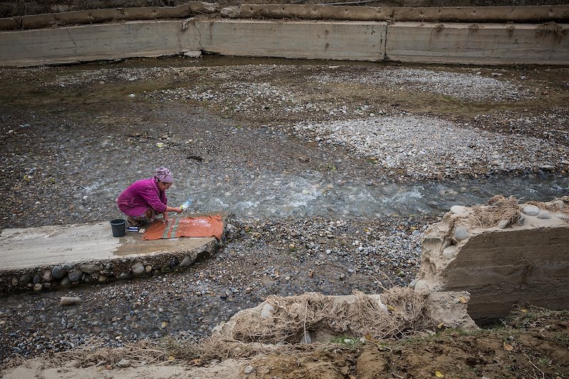A woman washes her carpet in the river which is also the source of drinking water.