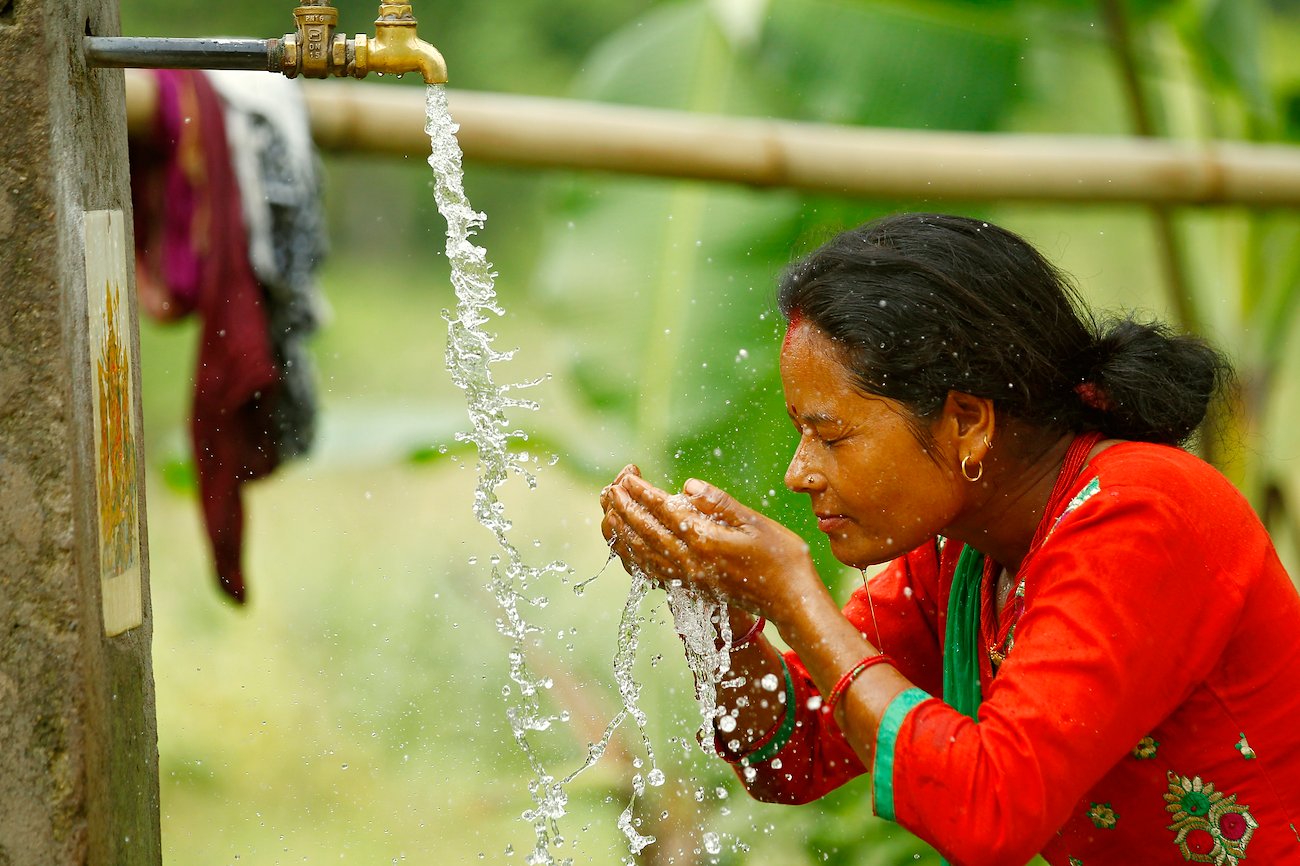 Nepalese woman washes at a communal water tap. Photo: UN Women/Narendra Shrestha