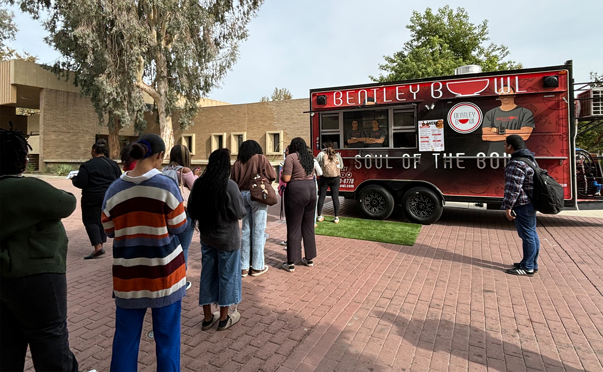 Students line up to get food from the Bentley Bowl truck during a stop ...