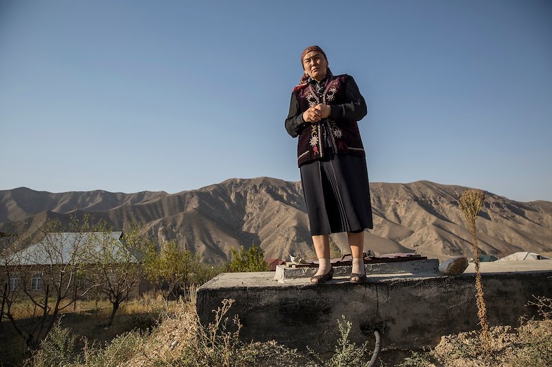 School principal Zhumagul Tolukbaeva stands on a water reservoir used in Lyaily village, served by water that trickles down from a spring.