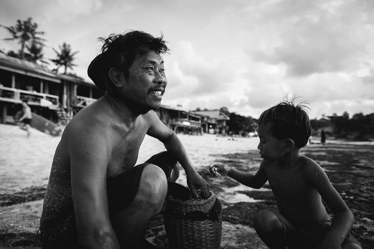 Balinese fisherman and a small boy are checking his catch